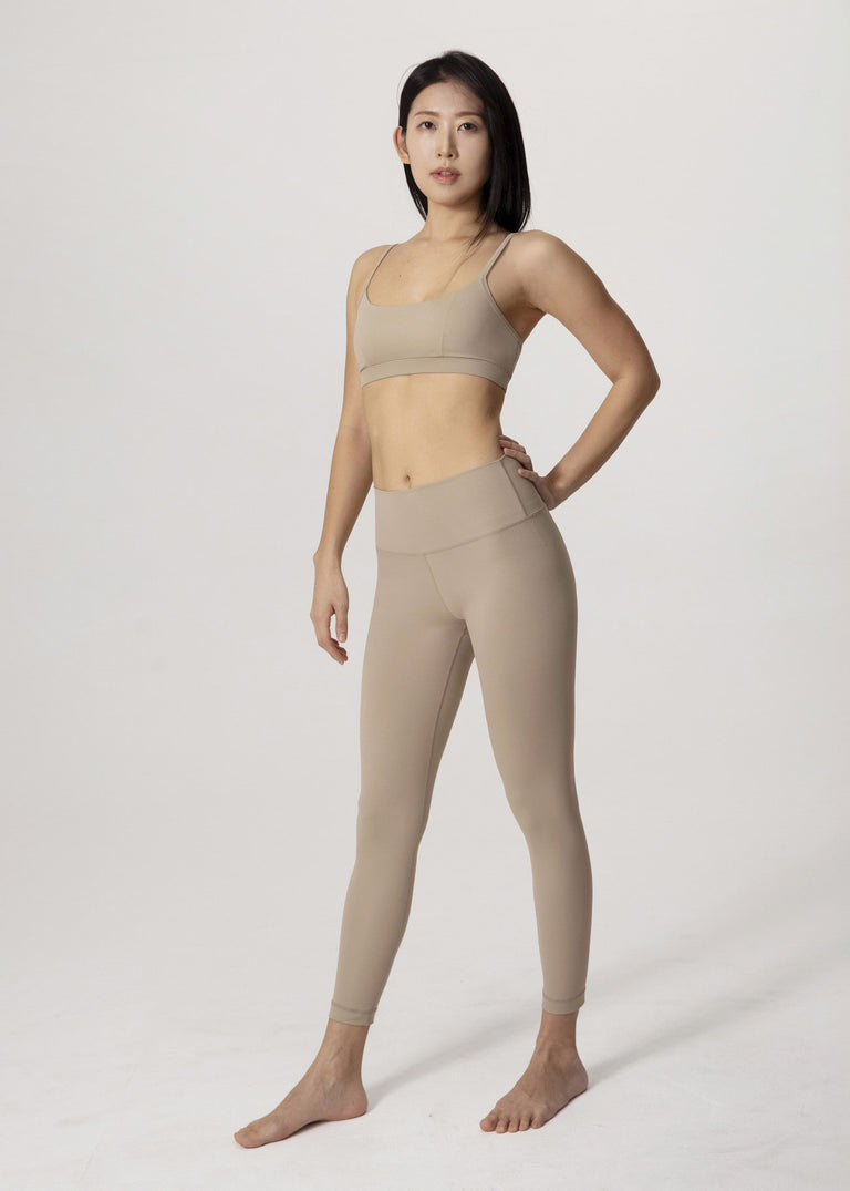 Front view of model standing in beige Flowmango Inner Flow leggings with matching bra
