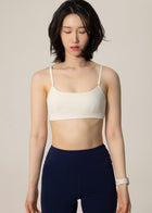 Front view of model wearing ivory Flowmango Inner Flow bra and navy leggings while looking down