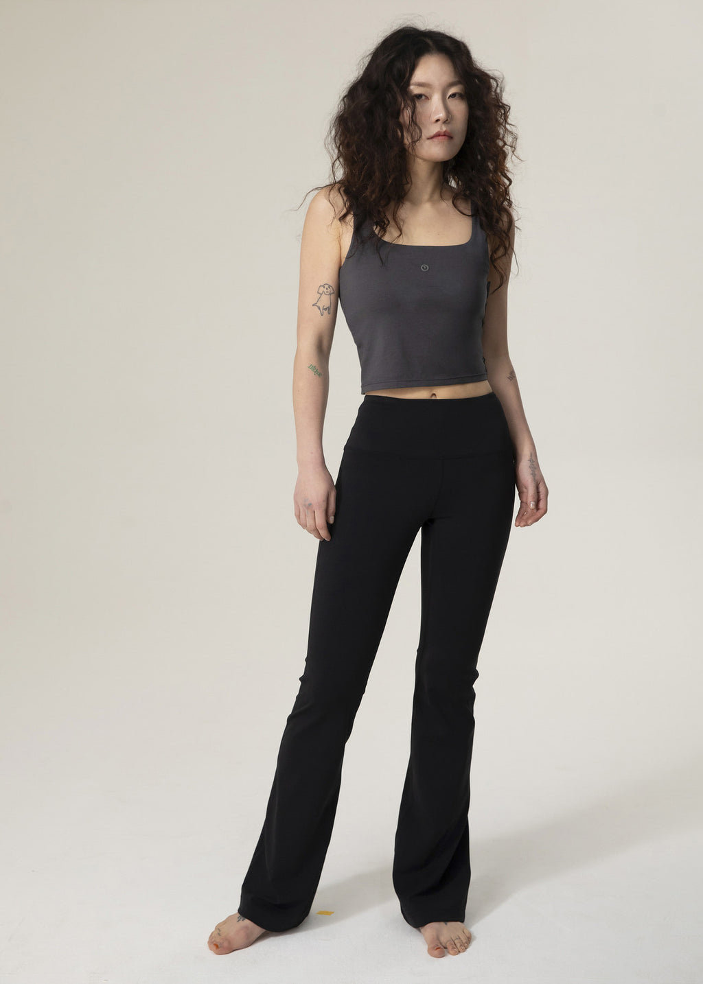 Front view of model wearing black Flowmango flared leggings with a charcoal tank top