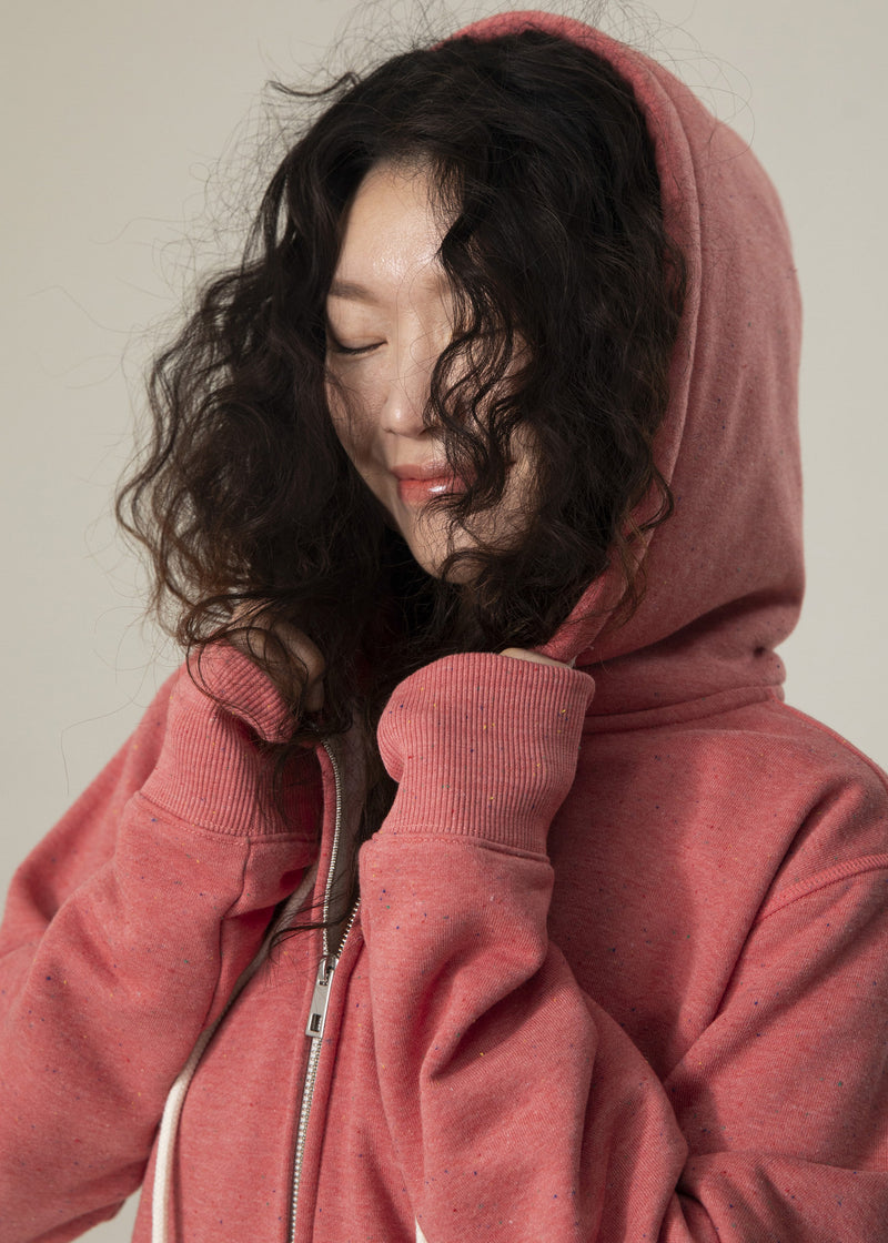 Close-up of model wearing the hood of the dusty rose Dot Flow zip-up hoodie with ribbed cuffs