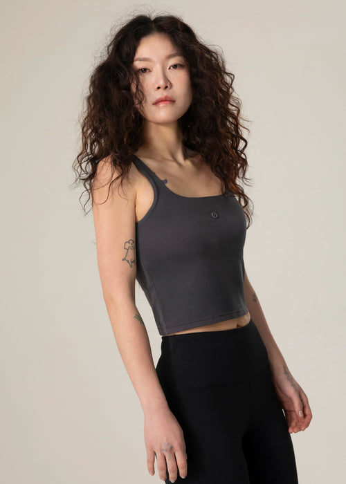 Model wearing the charcoal Urban Flow Tank Top with black leggings, front three-quarter view