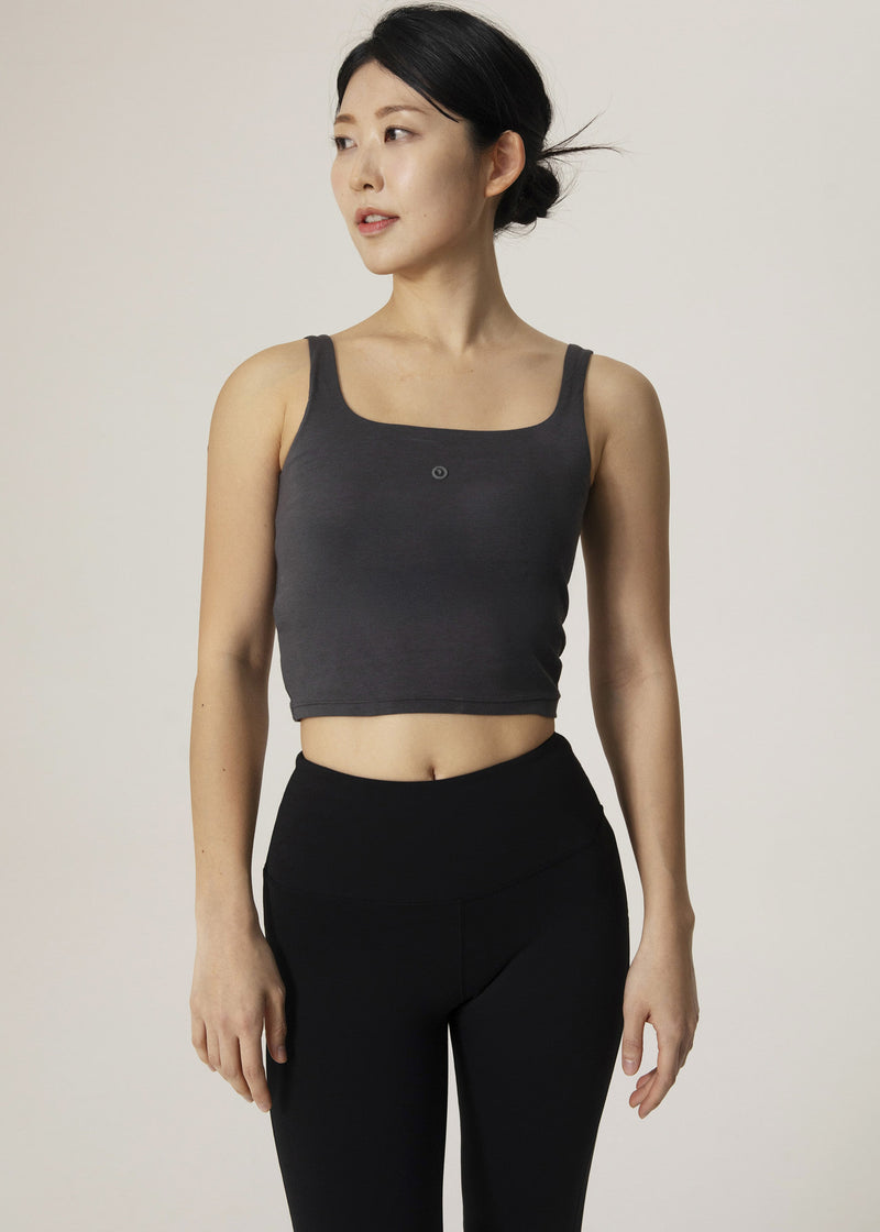 Front view of model wearing the charcoal Urban Flow Tank Top with black leggings
