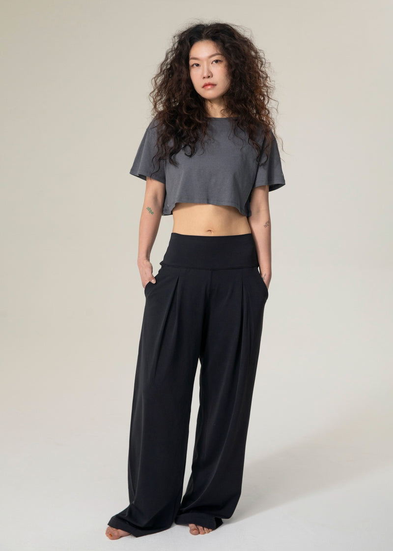 Front view of model wearing black Flowmango Deep Flow wide-leg pants with a charcoal cropped top