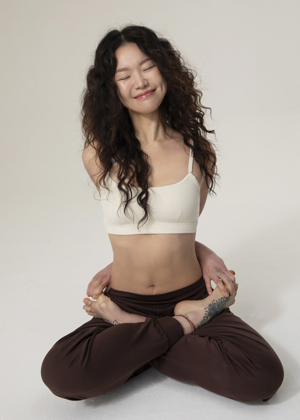 Seated model smiling in brown Flowmango jogger pants