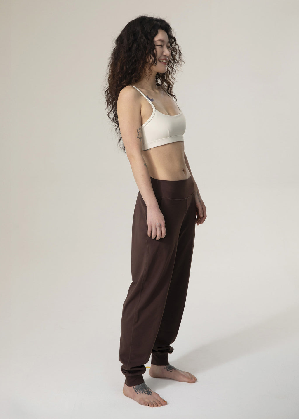 Side view of model standing in brown Flowmango jogger pants