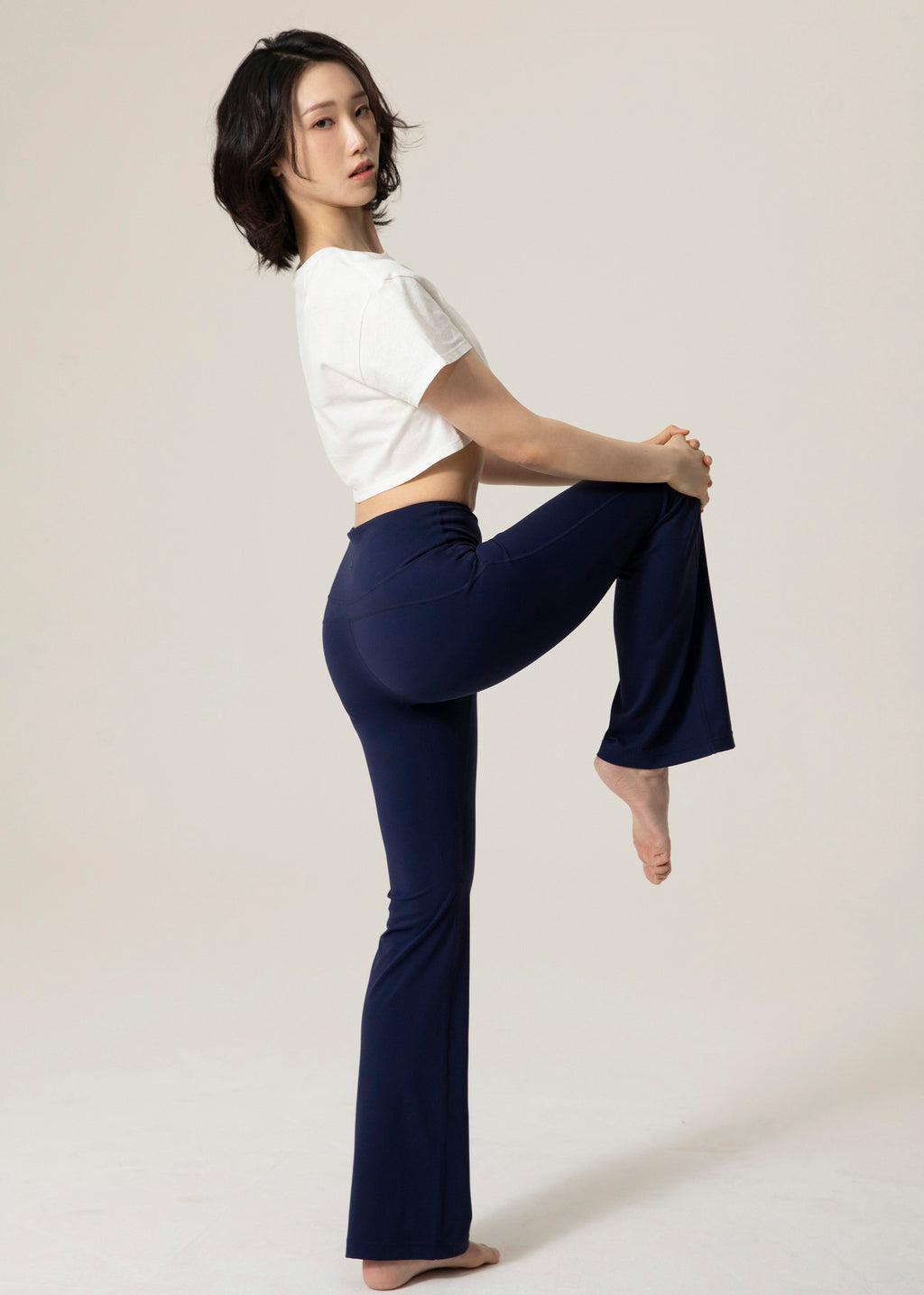 Side view of model in navy Deep Flow Flared Leggings lifting one knee