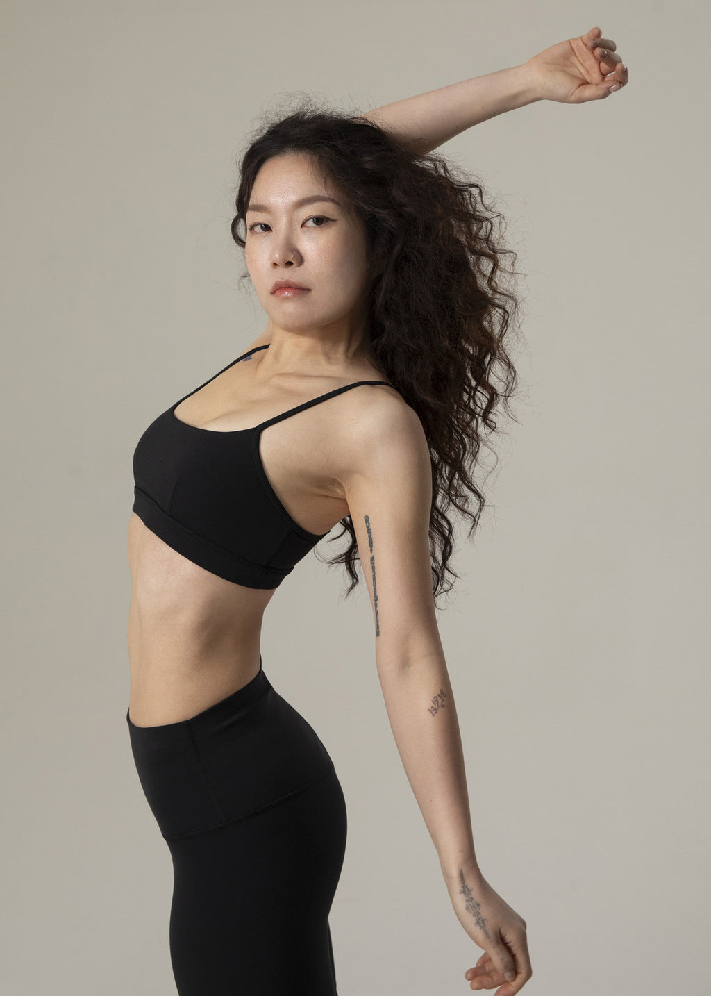 Three-quarter side view of model wearing black Flowmango Inner Flow bra with black leggings