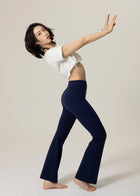 Model wearing navy Deep Flow Flared Leggings in side view with arms extended