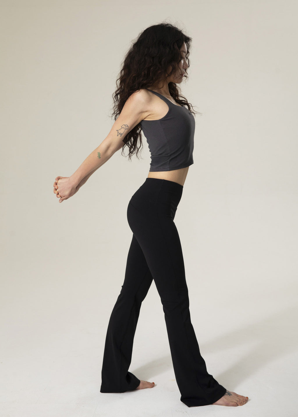 Side view of model walking in black Flowmango flared leggings