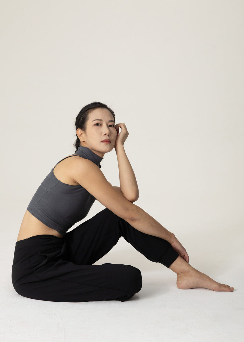Seated model wearing black Flowmango jogger pants with one knee bent