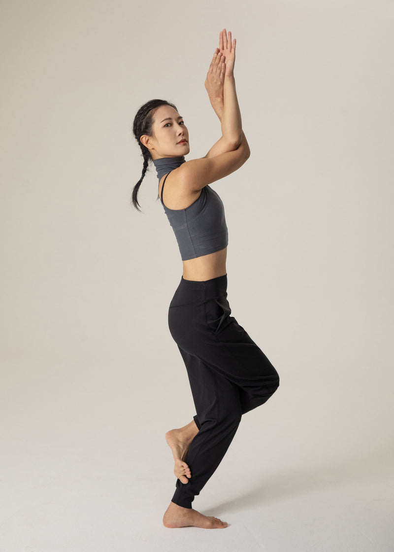 Side view of model raising both arms while wearing black Flowmango jogger pants