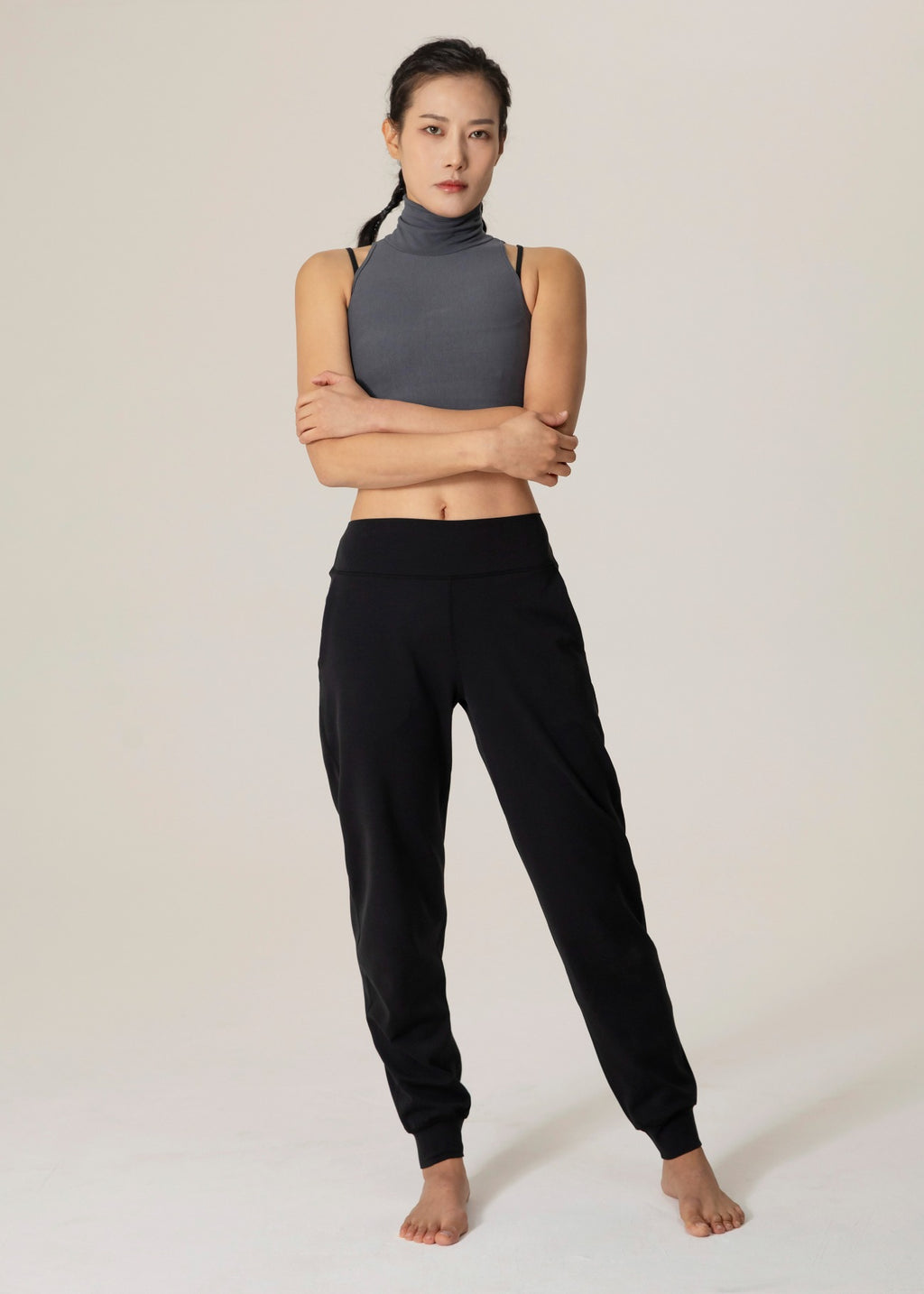 Front view of model standing with arms crossed in black Flowmango jogger pants