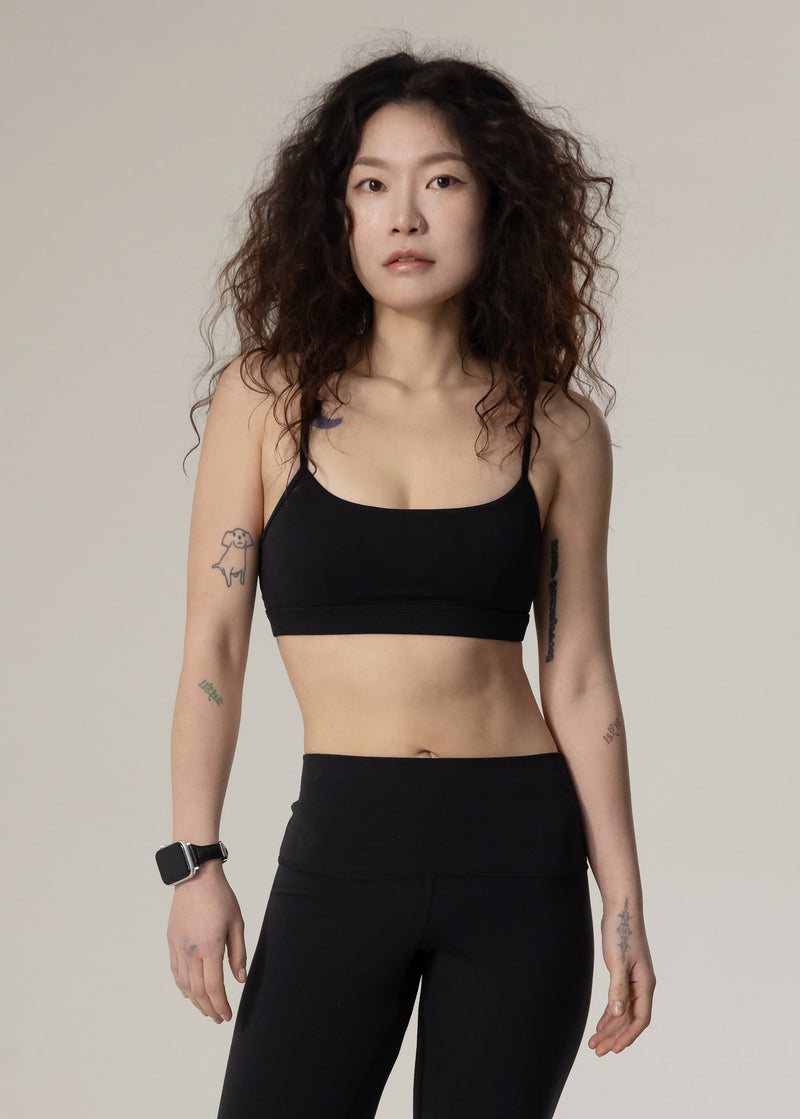 Front view of model wearing black Flowmango Inner Flow bra with black leggings